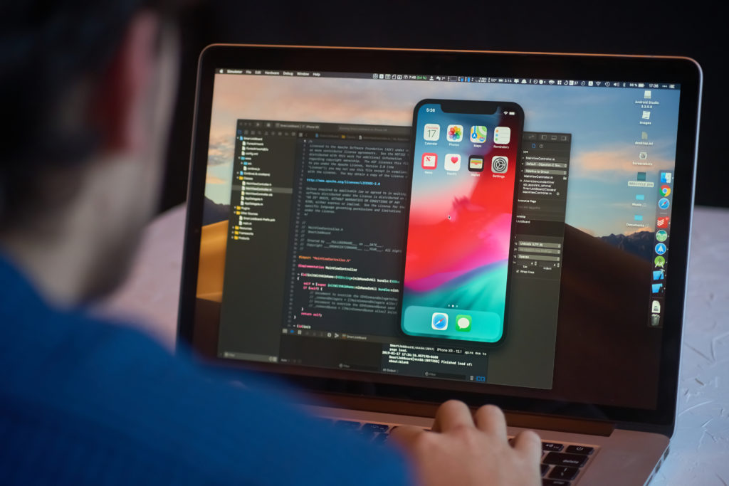 Man opens an iPhone simulator on a laptop usning Xcode