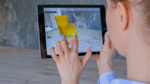 Woman using augmented reality app on an iPad to place a chair in a room